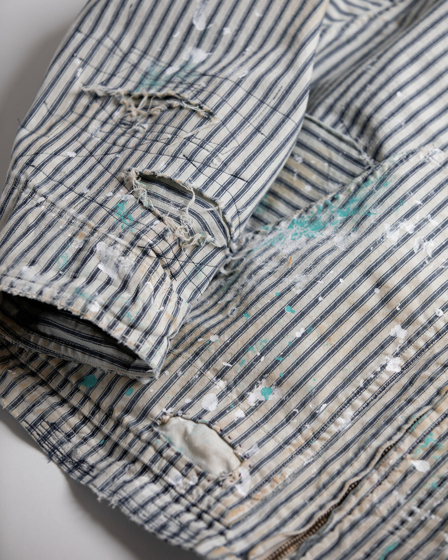 ゆとりある身幅とややクロップド丈でレイヤードを楽しめるデザインにしたヒッコリージャケット。
岡山県製9ozヒッコリーストライプ生地を使用し、ハリのあるしっかりとした風合いが特徴。
全体にエイジングとハードダメージを施し、手作業のステッチ補修とランダムなペンキでリアルな表情に仕上げています。