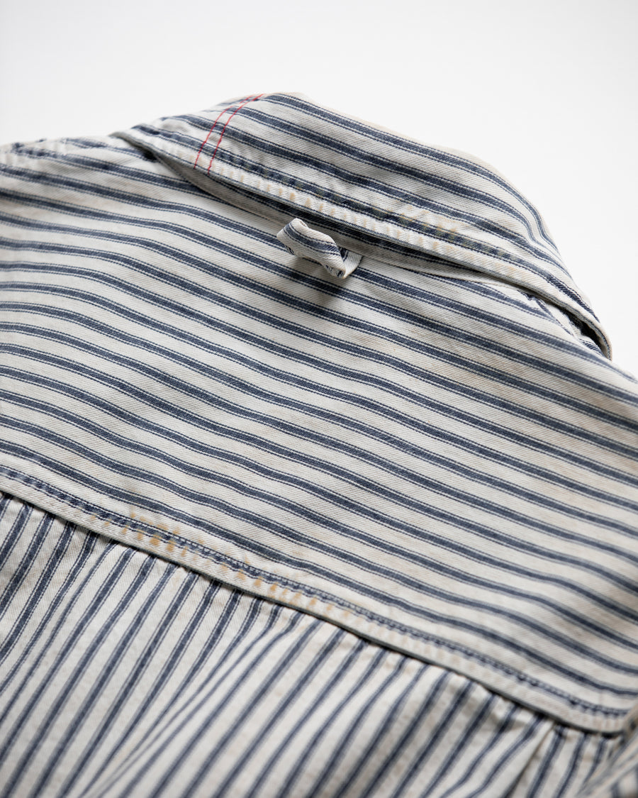 ゆとりある身幅とややクロップド丈でレイヤードを楽しめるデザインにしたヒッコリージャケット。
岡山県製9ozヒッコリーストライプ生地を使用し、ハリのあるしっかりとした風合いが特徴。
全体にエイジングとハードダメージを施し、手作業のステッチ補修とランダムなペンキでリアルな表情に仕上げています。