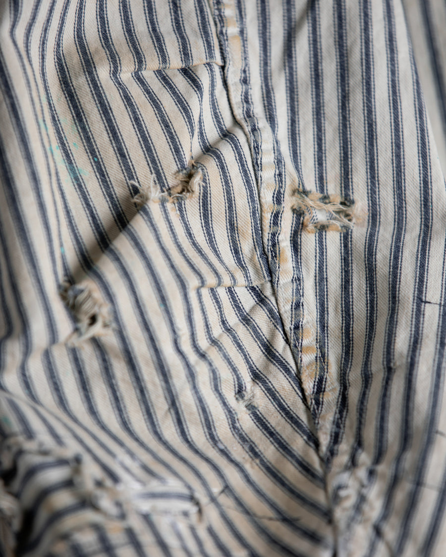 ゆとりある身幅とややクロップド丈でレイヤードを楽しめるデザインにしたヒッコリージャケット。
岡山県製9ozヒッコリーストライプ生地を使用し、ハリのあるしっかりとした風合いが特徴。
全体にエイジングとハードダメージを施し、手作業のステッチ補修とランダムなペンキでリアルな表情に仕上げています。