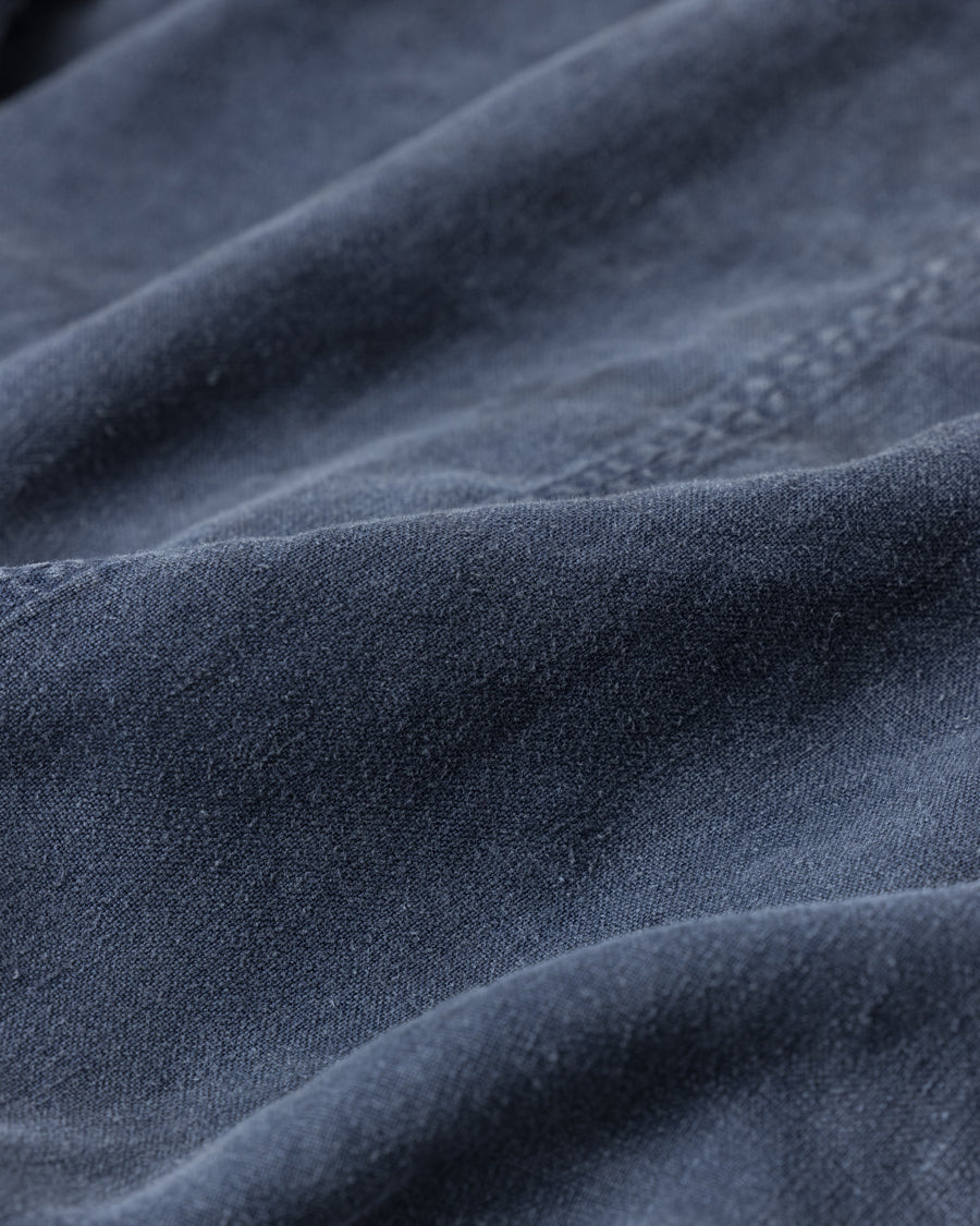 利便性の高い多機能ポケットを備えた、フレンチリネンのユーティリティジャケット。肉厚ながら「とろみ」のある柔らかなフレンチリネンを採用し、清涼感のある着心地を実現しました。硫化染め後に水を使用しないサスティナブルブリーチ加工を施すことで、環境に配慮しながらも、長年着込んだような深みのある色褪せとヴィンテージライクな佇まいを表現しています。

A utility jacket featuring functional pockets and a relaxed silhouette. Crafted from thick yet supple French Linen for a cool, soft touch. This NAVY piece undergoes a sulfur-dye and waterless sustainable bleach process, authentically recreating a deep, sun-faded vintage character while staying eco-conscious.