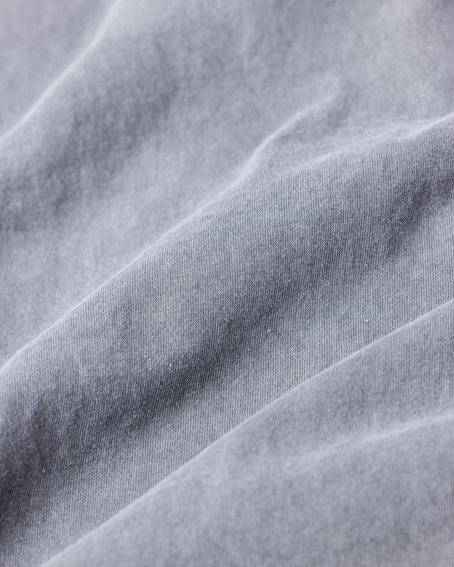 こだわりのオリジナルカラーで仕上げたロングスリーブTシャツ。幾度もの染色テストを重ね、他にはない絶妙な色味を追求しました。素材にはローゲージで編み立てたコットン天竺を採用し、程よい厚みとクリアな質感を両立。特殊顔料染めを施すことで、グレーの柔らかな発色の中に奥行きのある表情と、独特なこなれ感を引き出しています。

A long-sleeve T-shirt featuring a meticulously developed original color. Crafted from a relatively low-gauge cotton jersey for a clean yet structured look. This GRAY piece is treated with a special pigment dye, achieving a unique depth of color and a sophisticated, lived-in texture that results from extensive color testing.