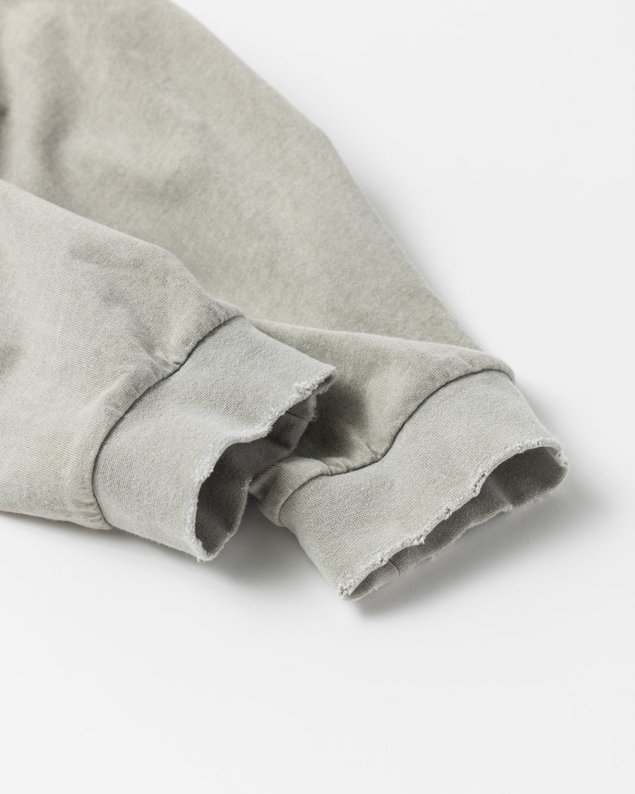 こだわりのオリジナルカラーで仕上げたロングスリーブTシャツ。幾度もの染色テストを重ね、他にはない絶妙な色味を追求しました。素材にはローゲージで編み立てたコットン天竺を採用し、程よい厚みとクリアな質感を両立。特殊顔料染めを施すことで、BEIGEの柔らかな発色の中に奥行きのある表情と、独特なこなれ感を引き出しています。

A long-sleeve T-shirt featuring a meticulously developed original color. Crafted from a relatively low-gauge cotton jersey for a clean yet structured look. This BEIGE piece is treated with a special pigment dye, achieving a unique depth of color and a sophisticated, lived-in texture that results from extensive color testing.