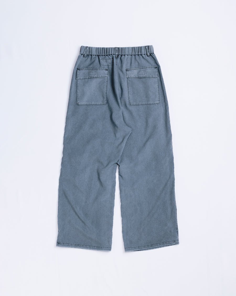 ポリエステル100％ながら、綿のような質感と軽量性を備えた高機能素材を採用。タスラン加工糸によるポリエステルオックスは、シワになりにくく速乾性にも優れています。染色が困難なポリエステルに特殊顔料染めを施すことで、化繊特有の光沢を抑え、ナチュラルで奥行きのある絶妙なフェード感と落ち着いた表情を実現しました。

High-performance polyester oxford with a cotton-like touch, offering quick-dry and wrinkle-resistant benefits. This GRAY BLUE item features a special pigment dye—a rare process for polyester—achieving a sophisticated, faded texture and a matte finish that perfectly balances technical utility with a natural, lived-in aesthetic.