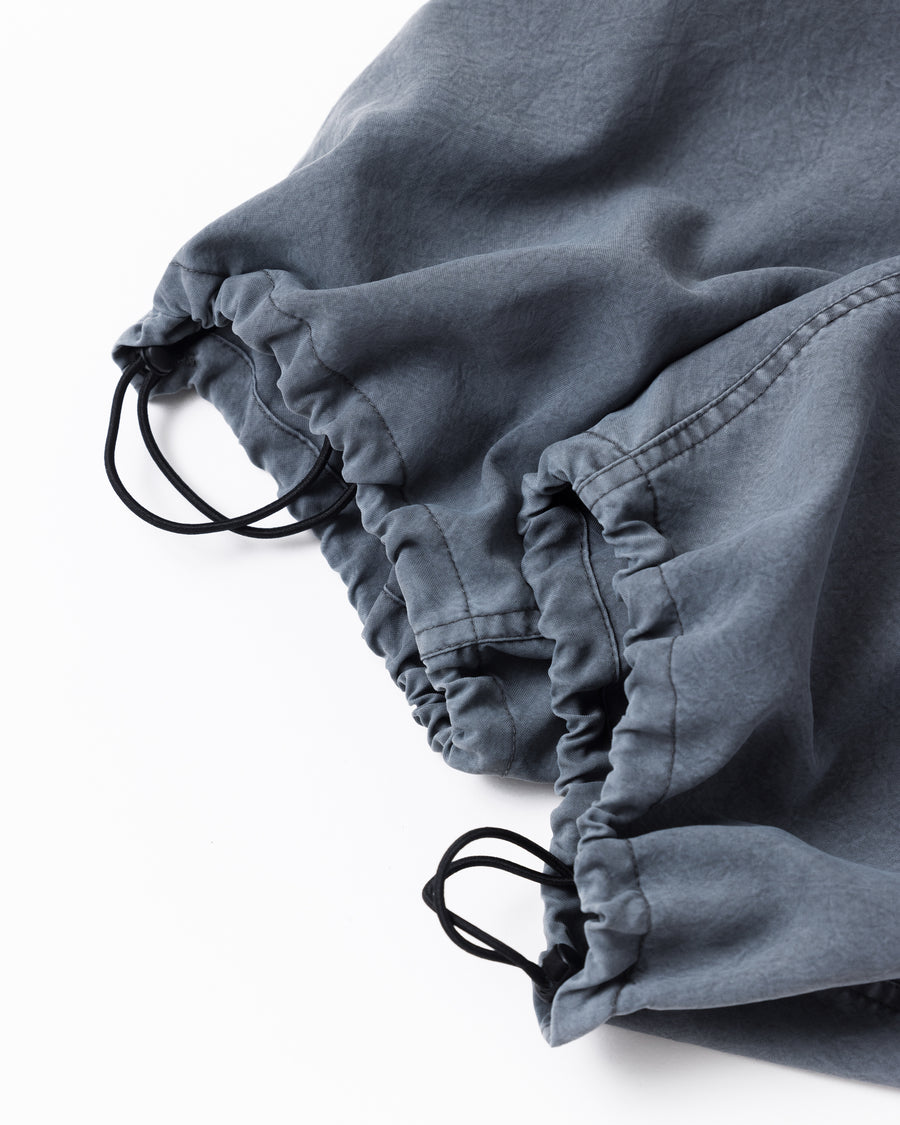 ポリエステル100％ながら、綿のような質感と軽量性を備えた高機能素材を採用。タスラン加工糸によるポリエステルオックスは、シワになりにくく速乾性にも優れています。染色が困難なポリエステルに特殊顔料染めを施すことで、化繊特有の光沢を抑え、ナチュラルで奥行きのある絶妙なフェード感と落ち着いた表情を実現しました。

High-performance polyester oxford with a cotton-like touch, offering quick-dry and wrinkle-resistant benefits. This GRAY BLUE item features a special pigment dye—a rare process for polyester—achieving a sophisticated, faded texture and a matte finish that perfectly balances technical utility with a natural, lived-in aesthetic.