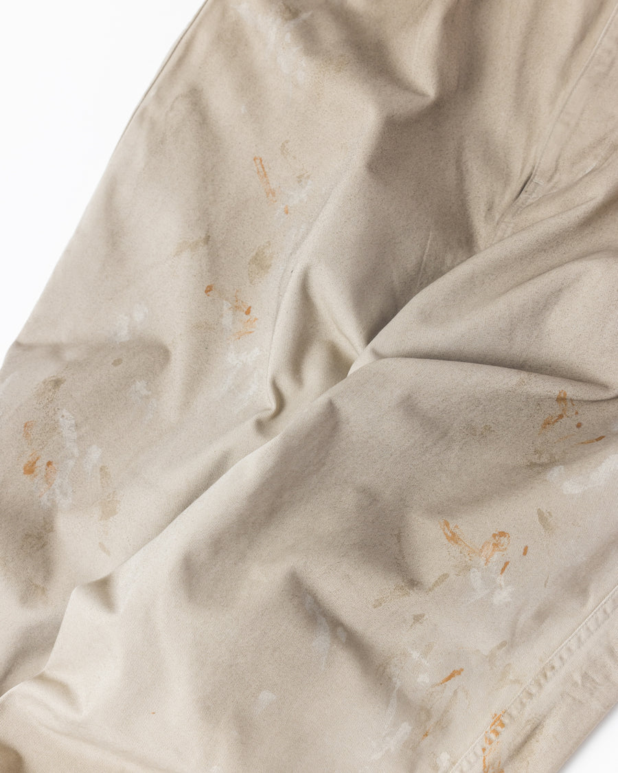 フロントに2タックを施し、ワタリから裾にかけてゆとりを持たせたワイルドなワイドシルエット。裾のドローコードでシルエットの変化も自在に楽しめます。素材には耐久性に優れ、綾織特有の柔らかさを持つ厚手チノクロスを採用。ストーンバイオウォッシュと汚し加工を重ねることで、長年穿き込んだようなリアルな質感と深みのある表情を引き出しました。

Wild, wide-silhouette pants with double-tucked fronts and adjustable hem drawcords. Crafted from durable, soft chino cloth, this BEIGE pair features a stone bio-wash and staining process. This creates an authentic, rugged texture and a deeply weathered look, blending vintage workwear aesthetics with a modern, voluminous fit.