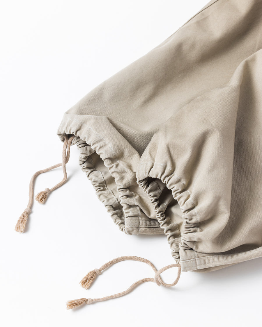 フロントに2タックを施し、ワタリから裾にかけてゆとりを持たせたワイルドなワイドシルエット。裾のドローコードでシルエットの変化も自在に楽しめます。素材には耐久性に優れ、綾織特有の柔らかさを持つ厚手チノクロスを採用。ストーンバイオウォッシュと汚し加工を重ねることで、長年穿き込んだようなリアルな質感と深みのある表情を引き出しました。

Wild, wide-silhouette pants with double-tucked fronts and adjustable hem drawcords. Crafted from durable, soft chino cloth, this BEIGE pair features a stone bio-wash and staining process. This creates an authentic, rugged texture and a deeply weathered look, blending vintage workwear aesthetics with a modern, voluminous fit.