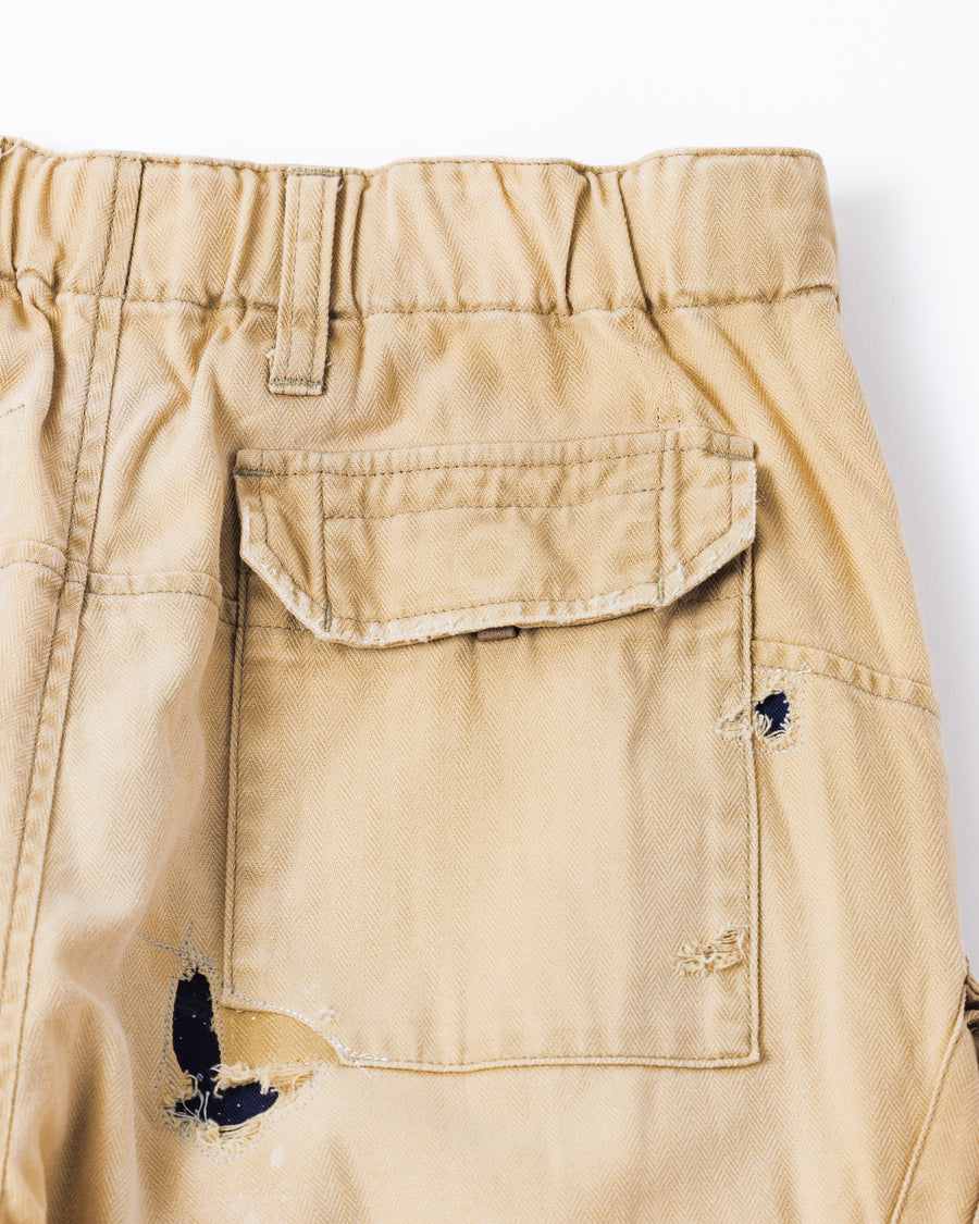 ミリタリートラウザーズを現代的にリファイン。斜めのカーゴポケットが実用的なアクセントを添え、洗練されたテーパードラインが際立ちます。素材には肌馴染みの良い10sヘリンボンを採用。環境に配慮した特殊エイジング・サンフェード加工と随所のリメイクにより、リアリティのある褪色感とヴィンテージな佇まいを表現しました。

Modernized military trousers with a refined tapered fit and slanted cargo pockets. Crafted from soft 10s herringbone, this KHAKI pair features special sun-fading and remake details. It achieves an authentic, time-worn vintage character while utilizing eco-conscious processing to minimize environmental impact.