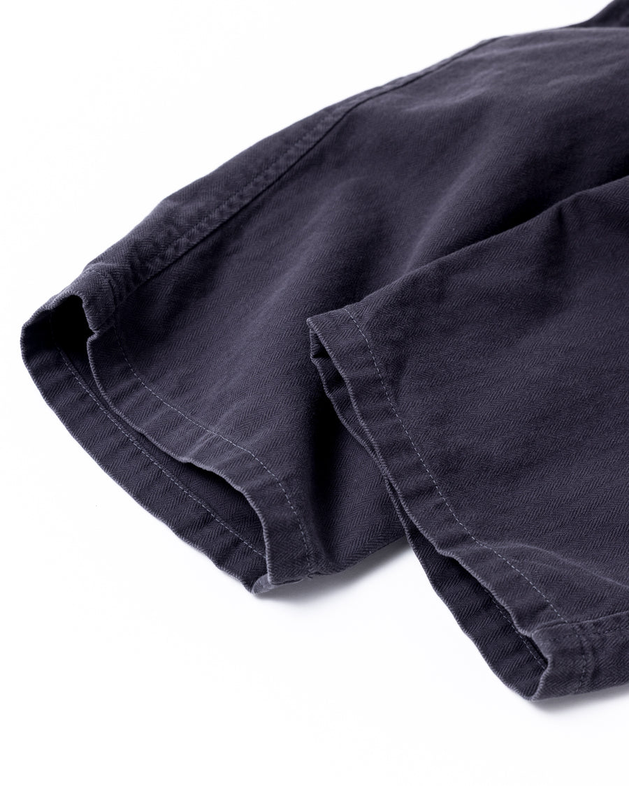 ミリタリートラウザーズをベースに、シルエットを現代的にリファイン。印象的な斜めのカーゴポケットが、立体感と実用性を両立させています。裾にかけて緩やかに絞られたテーパードラインにより、無骨ながらも洗練された印象に。素材には肌馴染みの良い10sヘリンボンを採用し、ストーンバイオウォッシュで柔らかな風合いとこなれ感を引き出しました。

Military trousers refined with a modern tapered silhouette. The distinctive slanted cargo pockets offer both practical utility and a structured look. Crafted from soft, classic 10s herringbone, this CHARCOAL pair has been treated with a stone bio-wash, providing a comfortable, worn-in texture and a sophisticated take on rugged style.