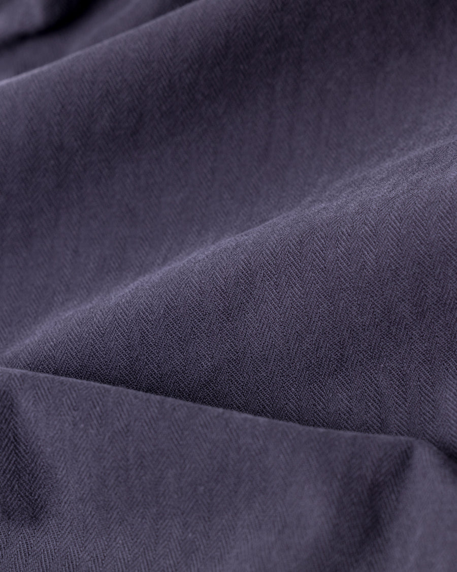 ミリタリートラウザーズをベースに、シルエットを現代的にリファイン。印象的な斜めのカーゴポケットが、立体感と実用性を両立させています。裾にかけて緩やかに絞られたテーパードラインにより、無骨ながらも洗練された印象に。素材には肌馴染みの良い10sヘリンボンを採用し、ストーンバイオウォッシュで柔らかな風合いとこなれ感を引き出しました。

Military trousers refined with a modern tapered silhouette. The distinctive slanted cargo pockets offer both practical utility and a structured look. Crafted from soft, classic 10s herringbone, this CHARCOAL pair has been treated with a stone bio-wash, providing a comfortable, worn-in texture and a sophisticated take on rugged style.