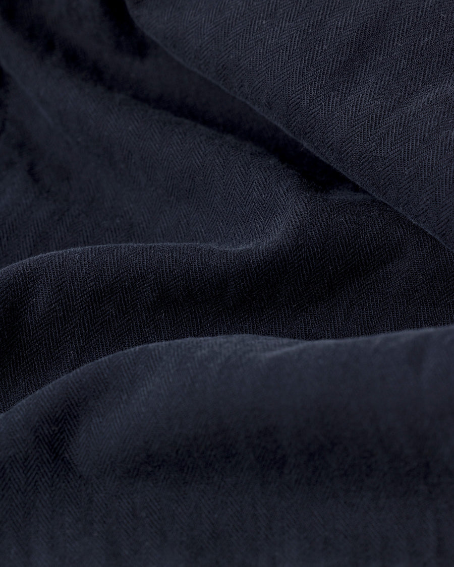 ミリタリートラウザーズをベースに、シルエットを現代的にリファイン。印象的な斜めのカーゴポケットが、立体感と実用性を両立させています。裾にかけて緩やかに絞られたテーパードラインにより、無骨ながらも洗練された印象に。素材には肌馴染みの良い10sヘリンボンを採用し、ストーンバイオウォッシュで柔らかな風合いとこなれ感を引き出しました。

Military trousers refined with a modern tapered silhouette. The distinctive slanted cargo pockets offer both practical utility and a structured look. Crafted from soft, classic 10s herringbone, this BLACK pair has been treated with a stone bio-wash, providing a comfortable, worn-in texture and a sophisticated take on rugged style.