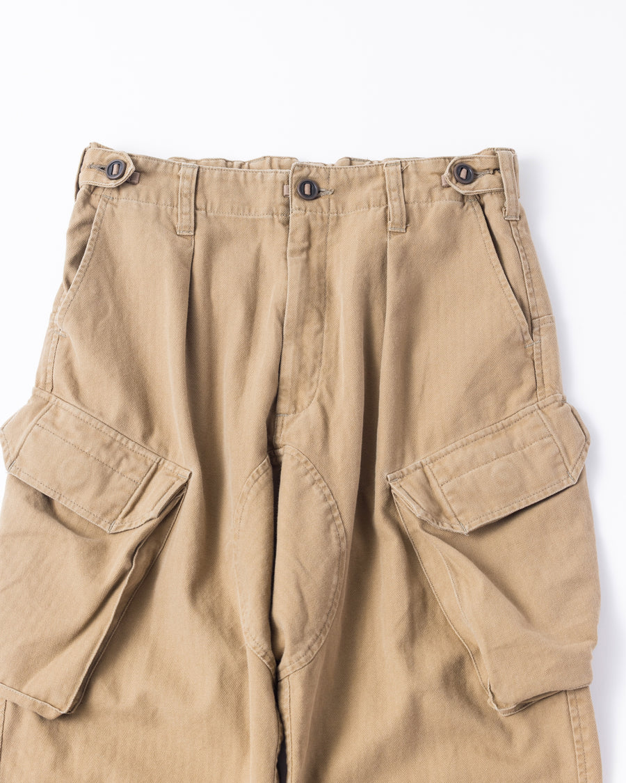 ミリタリートラウザーズをベースに、シルエットを現代的にリファイン。印象的な斜めのカーゴポケットが、立体感と実用性を両立させています。裾にかけて緩やかに絞られたテーパードラインにより、無骨ながらも洗練された印象に。素材には肌馴染みの良い10sヘリンボンを採用し、ストーンバイオウォッシュで柔らかな風合いとこなれ感を引き出しました。

Military trousers refined with a modern tapered silhouette. The distinctive slanted cargo pockets offer both practical utility and a structured look. Crafted from soft, classic 10s herringbone, this KHAKI pair has been treated with a stone bio-wash, providing a comfortable, worn-in texture and a sophisticated take on rugged style.