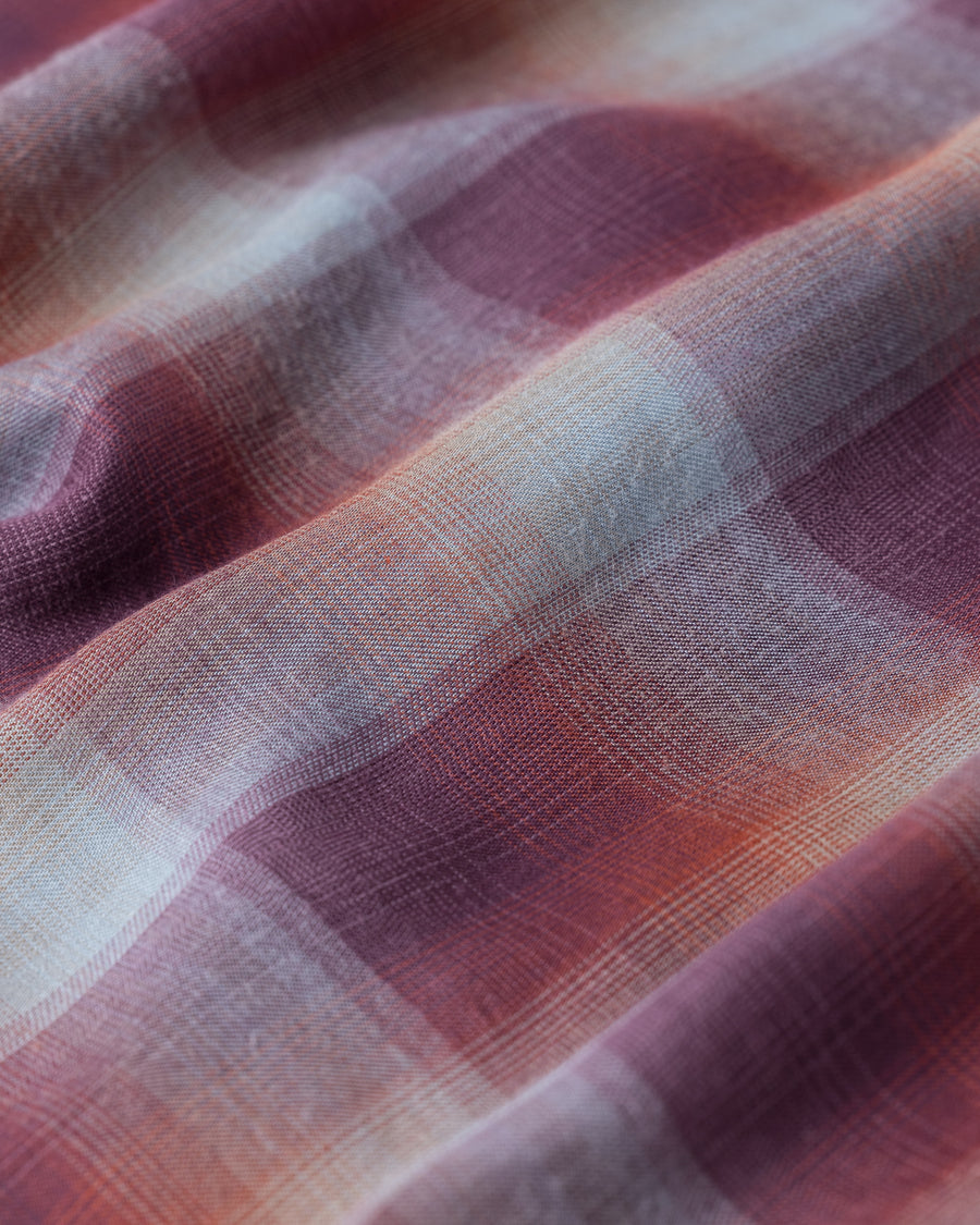 オンブレチェック柄が目を惹くオープンカラーシャツ。生地が持つ自然なドレープ感を活かし、リラックス感のあるゆとりを持たせたシルエットに仕上げました。素材にはタテ・ヨコ共にレーヨン糸を使用したレーヨンチェックを採用。非常に優れた落ち感と、袖を通した瞬間に感じる滑らかで心地よい肌触りが、上質なリラックススタイルを演出します。

An open-collar shirt featuring a classic ombre check pattern. The relaxed silhouette highlights the natural drape and fluid movement of the fabric. Crafted from a high-quality rayon check weave, this RED CHECK piece is characterized by its exceptional softness and smooth touch, offering a sophisticated look with an effortlessly comfortable feel.