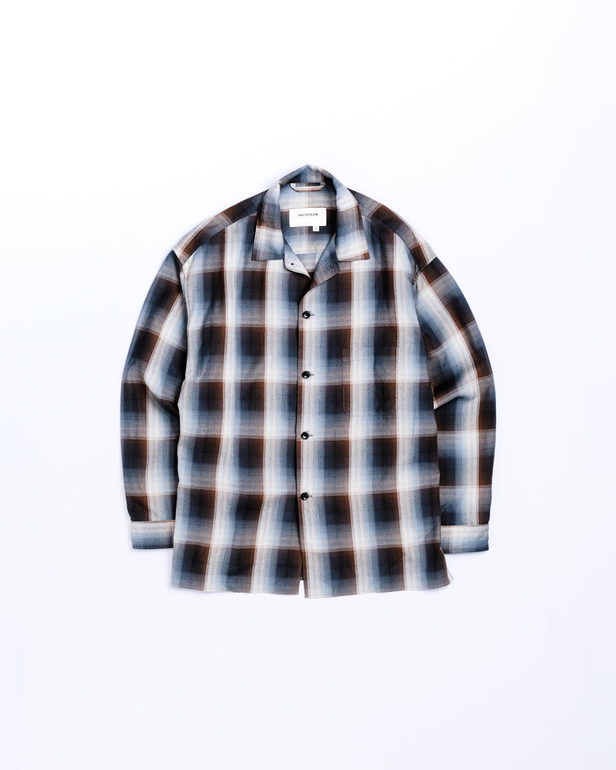 オンブレチェック柄が目を惹くオープンカラーシャツ。生地が持つ自然なドレープ感を活かし、リラックス感のあるゆとりを持たせたシルエットに仕上げました。素材にはタテ・ヨコ共にレーヨン糸を使用したレーヨンチェックを採用。非常に優れた落ち感と、袖を通した瞬間に感じる滑らかで心地よい肌触りが、上質なリラックススタイルを演出します。

An open-collar shirt featuring a classic ombre check pattern. The relaxed silhouette highlights the natural drape and fluid movement of the fabric. Crafted from a high-quality rayon check weave, this BLUE CHECK piece is characterized by its exceptional softness and smooth touch, offering a sophisticated look with an effortlessly comfortable feel.
