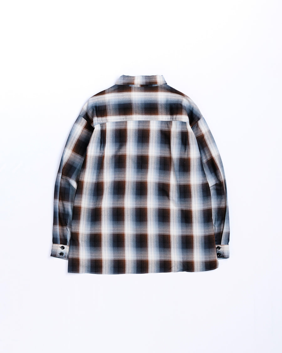 オンブレチェック柄が目を惹くオープンカラーシャツ。生地が持つ自然なドレープ感を活かし、リラックス感のあるゆとりを持たせたシルエットに仕上げました。素材にはタテ・ヨコ共にレーヨン糸を使用したレーヨンチェックを採用。非常に優れた落ち感と、袖を通した瞬間に感じる滑らかで心地よい肌触りが、上質なリラックススタイルを演出します。

An open-collar shirt featuring a classic ombre check pattern. The relaxed silhouette highlights the natural drape and fluid movement of the fabric. Crafted from a high-quality rayon check weave, this BLUE CHECK piece is characterized by its exceptional softness and smooth touch, offering a sophisticated look with an effortlessly comfortable feel.