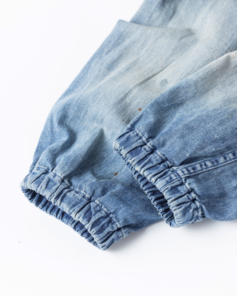 フード口のボタンの開閉により、首まわりのニュアンスを変えて楽しめる一着。素材には、経糸にコットンムラ糸、緯糸に綿麻混紡糸を使用した綿麻6ozデニムを採用しました。シャープなムラ感とリネン混ならではの粗野な風合いが、ヴィンテージの魅力を引き立てます。エイジング加工を施すことで、全体にリアリティのあるアタリ感を出し、長年着込んだような深みのある表情に仕上げました。A versatile piece featuring adjustable hood buttons to create a clean or relaxed neckline. Crafted from 6oz cotton-linen denim, the fabric combines sharp slub textures with a rustic linen feel for an authentic vintage character. Treated with an aging process to create realistic wear and fade, this INDIGO garment offers a sophisti