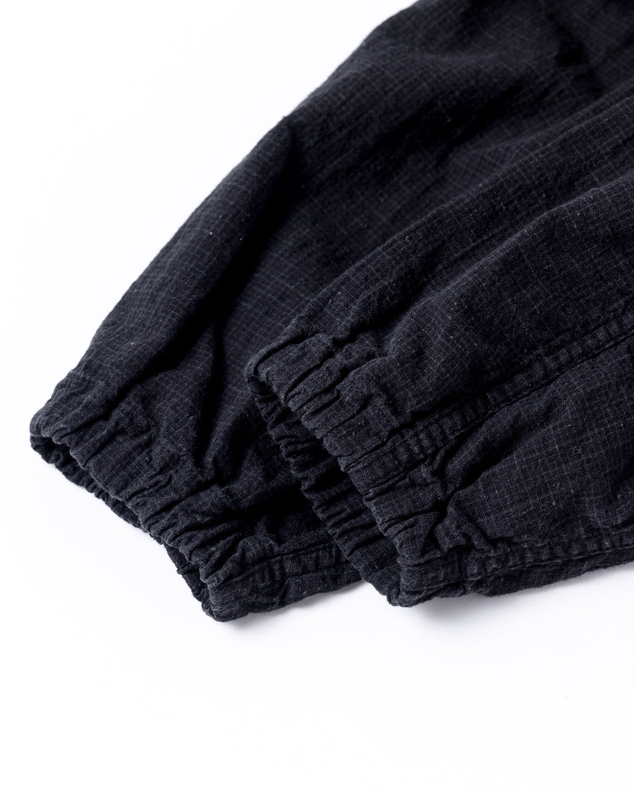 フード口のボタンの開閉により、首周りのニュアンスを自在に調整できる一着。素材には、麻カスや節を活かしたネップ糸を織り交ぜたコットンリネンチェックを採用しました。ドライタッチな生地にワンウォッシュを施すことで、麻特有のハリ感を残しつつ、肌馴染みの良い柔らかな風合いと豊かな表情を引き出しています。

This piece features adjustable hood buttons to alternate between a clean look and a relaxed neckline. Crafted from a cotton-linen check weave with rustic nep yarns, it highlights the natural texture of the fibers. The BLACK fabric is one-washed to balance a crisp, dry touch with a soft, broken-in feel, creating a sophisticated yet comfortable aesthetic.