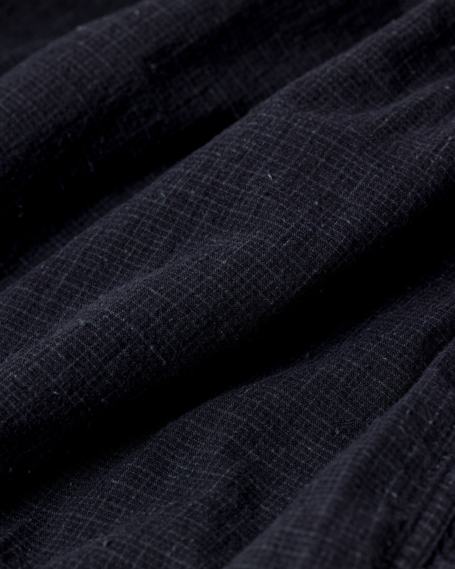 フード口のボタンの開閉により、首周りのニュアンスを自在に調整できる一着。素材には、麻カスや節を活かしたネップ糸を織り交ぜたコットンリネンチェックを採用しました。ドライタッチな生地にワンウォッシュを施すことで、麻特有のハリ感を残しつつ、肌馴染みの良い柔らかな風合いと豊かな表情を引き出しています。

This piece features adjustable hood buttons to alternate between a clean look and a relaxed neckline. Crafted from a cotton-linen check weave with rustic nep yarns, it highlights the natural texture of the fibers. The BLACK fabric is one-washed to balance a crisp, dry touch with a soft, broken-in feel, creating a sophisticated yet comfortable aesthetic.