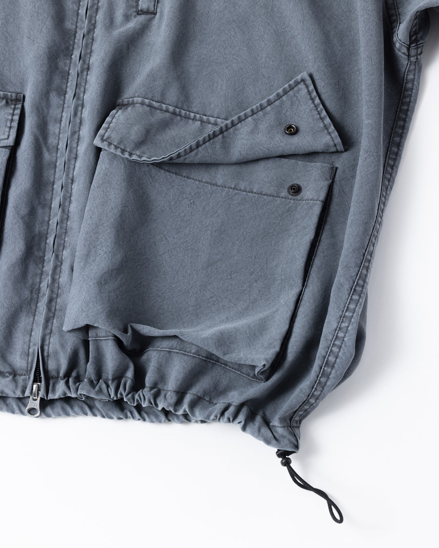 ポリエステル100％でありながら、綿のような質感と軽量性を備えた高機能な一着。タスラン加工糸を使用したポリエステルオックスを採用し、シワになりにくく速乾性に優れたイージーケア性を実現しました。本来染色が困難な素材に特殊顔料染めを施すことで、化繊特有の光沢を抑えた、ナチュラルで奥行きのある絶妙なフェード感を表現しています。

A high-performance piece crafted from polyester oxford, offering a cotton-like touch with lightweight, quick-dry, and wrinkle-resistant properties. This GRAY BLUE item features a special pigment dye—a rare process for polyester—achieving a sophisticated, faded texture and a matte finish that defies its synthetic origins.