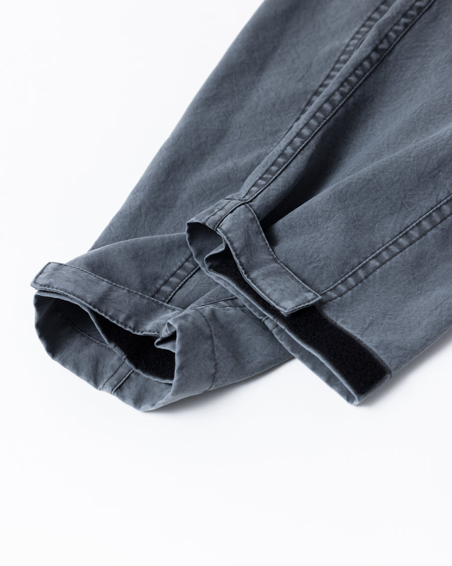 ポリエステル100％でありながら、綿のような質感と軽量性を備えた高機能な一着。タスラン加工糸を使用したポリエステルオックスを採用し、シワになりにくく速乾性に優れたイージーケア性を実現しました。本来染色が困難な素材に特殊顔料染めを施すことで、化繊特有の光沢を抑えた、ナチュラルで奥行きのある絶妙なフェード感を表現しています。

A high-performance piece crafted from polyester oxford, offering a cotton-like touch with lightweight, quick-dry, and wrinkle-resistant properties. This GRAY BLUE item features a special pigment dye—a rare process for polyester—achieving a sophisticated, faded texture and a matte finish that defies its synthetic origins.