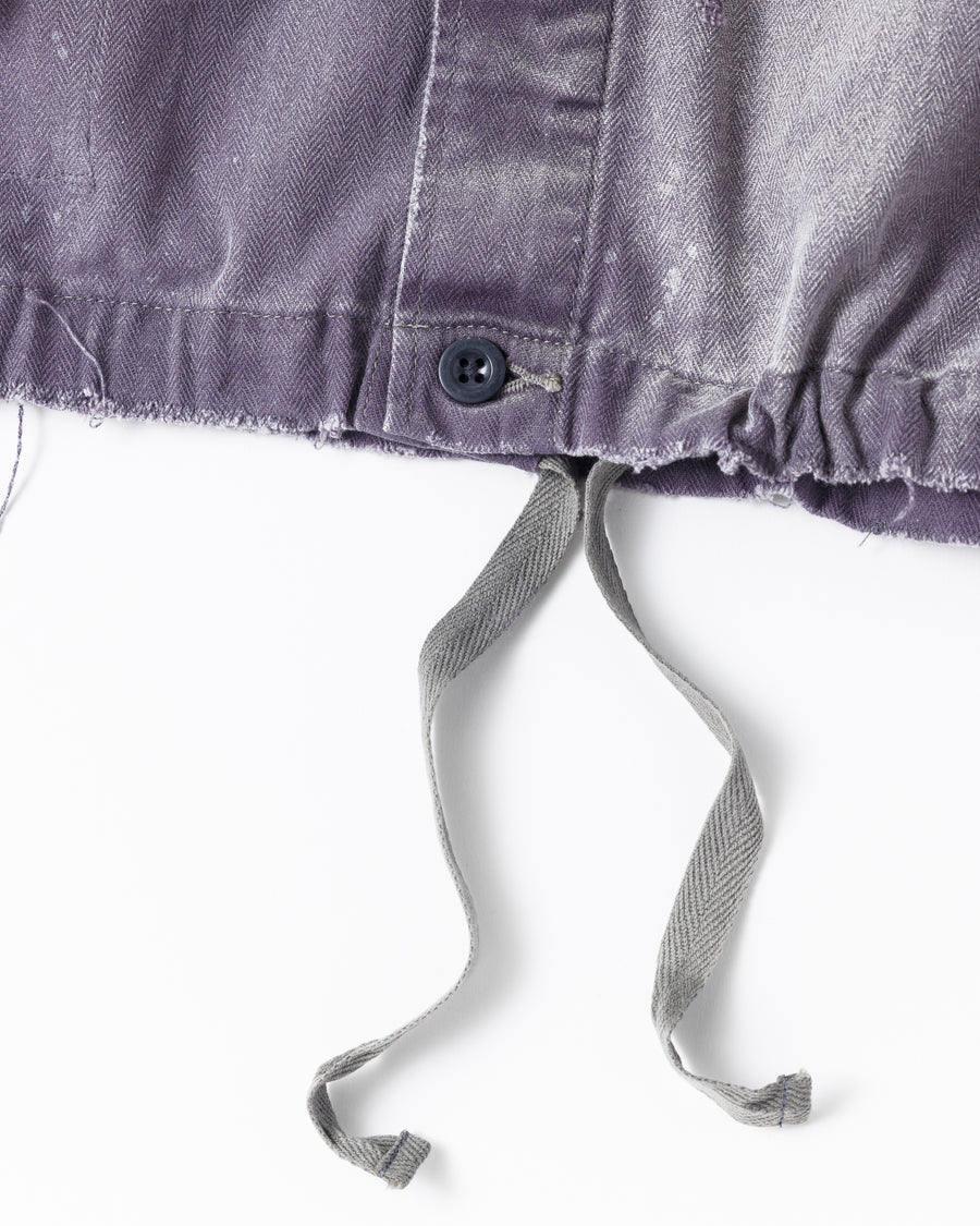 ミリタリーのシャツジャケットを現代的シルエットに更新。裾のドローコードでスタイルに合わせた変化を楽しめます。素材には肌馴染みの良い10sヘリンボンを採用。環境に配慮した特殊エイジング・サンフェード加工とダメージ加工を施すことで、クラシカルな生地にリアリティのある褪色感とヴィンテージライクな佇まいを表現しました。

A modern military shirt jacket with hem drawcords for an adjustable silhouette. Crafted from soft 10s herringbone, this CHARCOAL piece undergoes a special sun-fade and damage process. It achieves a realistic, time-worn vintage look with authentic distressing while minimizing environmental impact through eco-conscious processing.