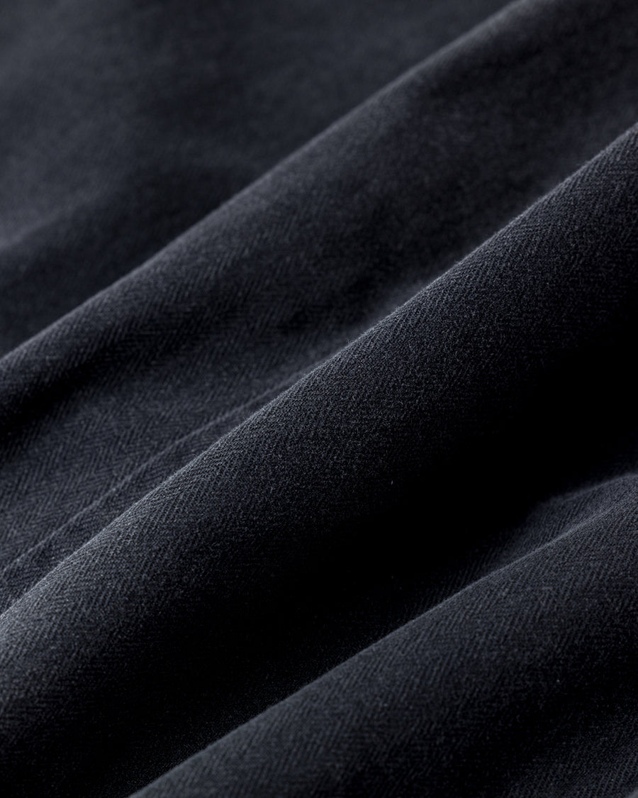 ミリタリーのシャツジャケットを現代的シルエットに更新。裾のドローコードでスタイルに合わせた変化を楽しめます。素材には肌馴染みの良い10sヘリンボンを採用。環境に配慮した特殊エイジング・サンフェード加工とダメージ加工を施すことで、クラシカルな生地にリアリティのある褪色感とヴィンテージライクな佇まいを表現しました。

A modern military shirt jacket with hem drawcords for an adjustable silhouette. Crafted from soft 10s herringbone, this BLACK piece undergoes a special sun-fade and damage process. It achieves a realistic, time-worn vintage look with authentic distressing while minimizing environmental impact through eco-conscious processing.