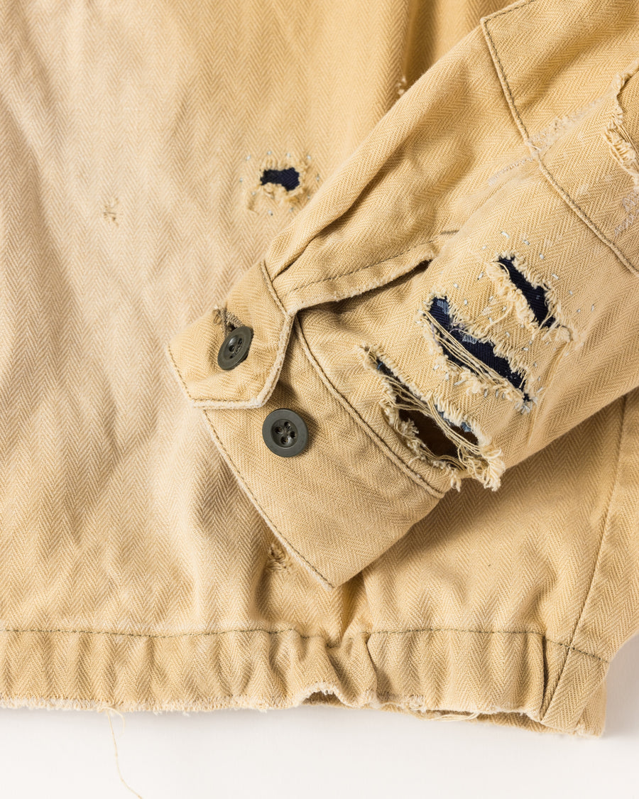 ミリタリーのシャツジャケットを現代的シルエットに更新。裾のドローコードでスタイルに合わせた変化を楽しめます。素材には肌馴染みの良い10sヘリンボンを採用。環境に配慮した特殊エイジング・サンフェード加工とダメージ加工を施すことで、クラシカルな生地にリアリティのある褪色感とヴィンテージライクな佇まいを表現しました。

A modern military shirt jacket with hem drawcords for an adjustable silhouette. Crafted from soft 10s herringbone, this KHAKI piece undergoes a special sun-fade and damage process. It achieves a realistic, time-worn vintage look with authentic distressing while minimizing environmental impact through eco-conscious processing.