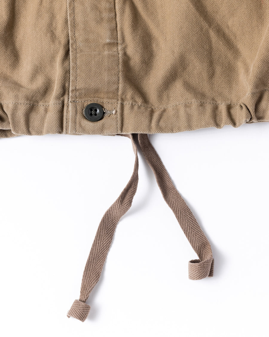 ミリタリーのシャツジャケットを現代的シルエットに更新。裾のドローコードで着丈のニュアンスを自在に調整可能です。素材には、やや甘織りで肌馴染みの良い10sヘリンボンを採用。ストーンバイオウォッシュを施すことで、クラシカルな生地感に柔らかな風合いとこなれ感をプラスした、着回し力の高い一着に仕上げました。

A modern update to the classic military shirt jacket, featuring hem drawcords for an adjustable silhouette. Crafted from 10s herringbone, slightly loose-knitted for a soft, comfortable touch. This KHAKI piece has been treated with a stone bio-wash, giving the traditional weave a natural, worn-in texture and a sophisticated casual feel.