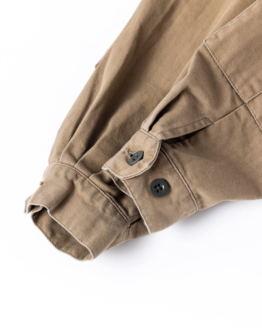 ミリタリーのシャツジャケットを現代的シルエットに更新。裾のドローコードで着丈のニュアンスを自在に調整可能です。素材には、やや甘織りで肌馴染みの良い10sヘリンボンを採用。ストーンバイオウォッシュを施すことで、クラシカルな生地感に柔らかな風合いとこなれ感をプラスした、着回し力の高い一着に仕上げました。

A modern update to the classic military shirt jacket, featuring hem drawcords for an adjustable silhouette. Crafted from 10s herringbone, slightly loose-knitted for a soft, comfortable touch. This KHAKI piece has been treated with a stone bio-wash, giving the traditional weave a natural, worn-in texture and a sophisticated casual feel.