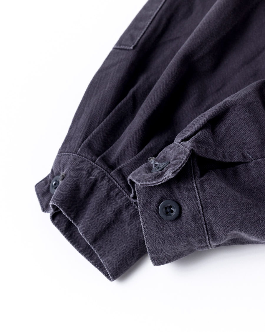 ミリタリーのシャツジャケットを現代的シルエットに更新。裾のドローコードで着丈のニュアンスを自在に調整可能です。素材には、やや甘織りで肌馴染みの良い10sヘリンボンを採用。ストーンバイオウォッシュを施すことで、クラシカルな生地感に柔らかな風合いとこなれ感をプラスした、着回し力の高い一着に仕上げました。

A modern update to the classic military shirt jacket, featuring hem drawcords for an adjustable silhouette. Crafted from 10s herringbone, slightly loose-knitted for a soft, comfortable touch. This CHARCOAL piece has been treated with a stone bio-wash, giving the traditional weave a natural, worn-in texture and a sophisticated casual feel.