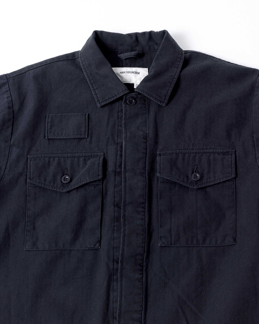 ミリタリーのシャツジャケットを現代的シルエットに更新。裾のドローコードで着丈のニュアンスを自在に調整可能です。素材には、やや甘織りで肌馴染みの良い10sヘリンボンを採用。ストーンバイオウォッシュを施すことで、クラシカルな生地感に柔らかな風合いとこなれ感をプラスした、着回し力の高い一着に仕上げました。

A modern update to the classic military shirt jacket, featuring hem drawcords for an adjustable silhouette. Crafted from 10s herringbone, slightly loose-knitted for a soft, comfortable touch. This BLACK piece has been treated with a stone bio-wash, giving the traditional weave a natural, worn-in texture and a sophisticated casual feel.