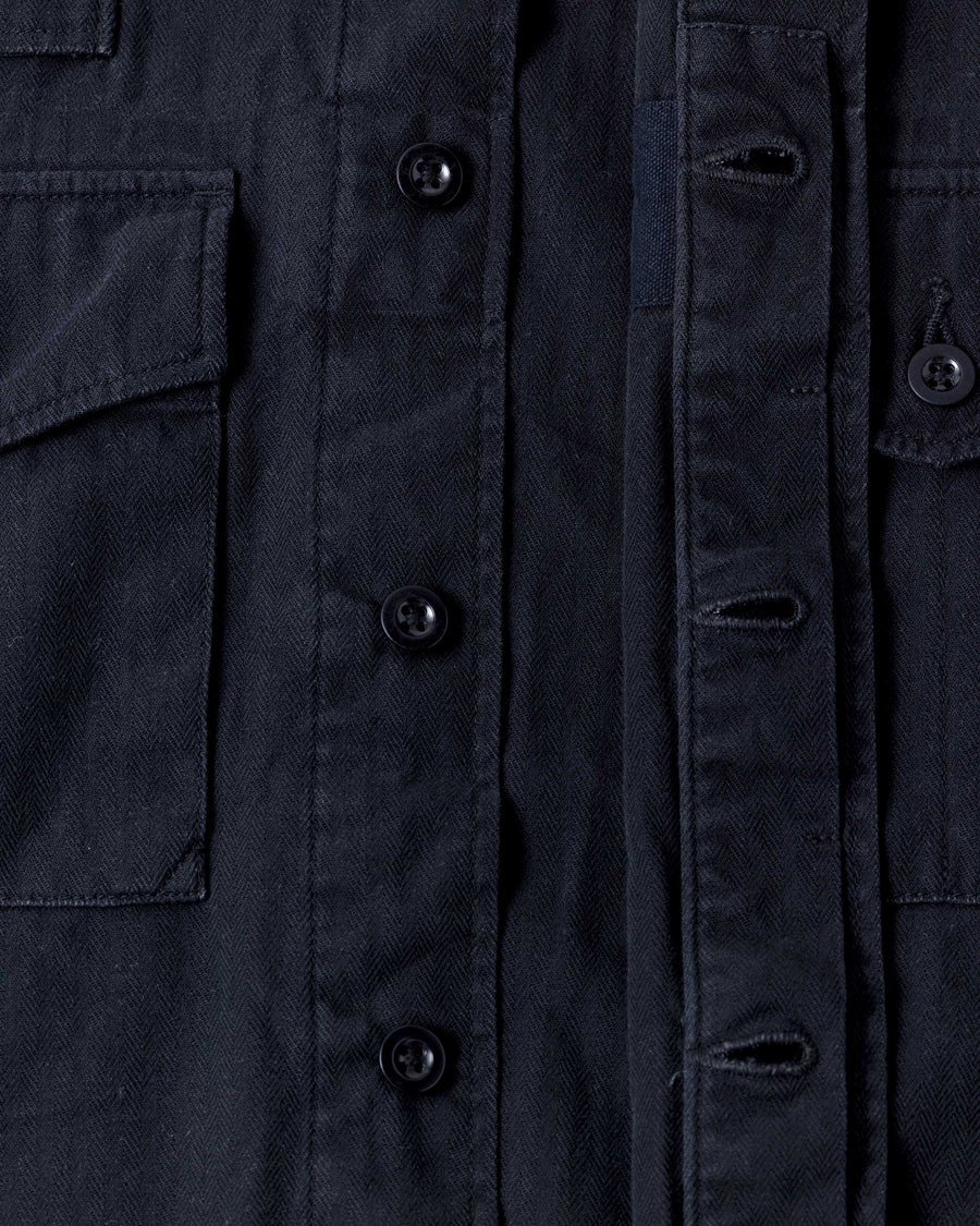 ミリタリーのシャツジャケットを現代的シルエットに更新。裾のドローコードで着丈のニュアンスを自在に調整可能です。素材には、やや甘織りで肌馴染みの良い10sヘリンボンを採用。ストーンバイオウォッシュを施すことで、クラシカルな生地感に柔らかな風合いとこなれ感をプラスした、着回し力の高い一着に仕上げました。

A modern update to the classic military shirt jacket, featuring hem drawcords for an adjustable silhouette. Crafted from 10s herringbone, slightly loose-knitted for a soft, comfortable touch. This BLACK piece has been treated with a stone bio-wash, giving the traditional weave a natural, worn-in texture and a sophisticated casual feel.