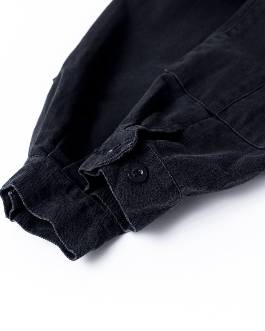 ミリタリーのシャツジャケットを現代的シルエットに更新。裾のドローコードで着丈のニュアンスを自在に調整可能です。素材には、やや甘織りで肌馴染みの良い10sヘリンボンを採用。ストーンバイオウォッシュを施すことで、クラシカルな生地感に柔らかな風合いとこなれ感をプラスした、着回し力の高い一着に仕上げました。

A modern update to the classic military shirt jacket, featuring hem drawcords for an adjustable silhouette. Crafted from 10s herringbone, slightly loose-knitted for a soft, comfortable touch. This BLACK piece has been treated with a stone bio-wash, giving the traditional weave a natural, worn-in texture and a sophisticated casual feel.