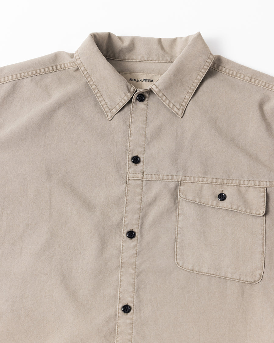 ポリエステル100％ながら、綿のような質感と軽量性を備えた高機能素材を採用。タスラン加工糸を使用したポリエステルオックスは、シワになりにくく速乾性にも優れています。本来染色が困難な素材に特殊顔料染めを施すことで、化繊特有の光沢を抑え、ナチュラルで奥行きのある絶妙なフェード感と落ち着いた表情を実現しました。

A high-performance piece crafted from polyester oxford, offering a cotton-like touch with quick-dry and wrinkle-resistant benefits. This GRAY BEIGE item features a special pigment dye—a rare process for polyester—achieving a sophisticated, faded texture and a matte finish that perfectly balances technical utility with a natural, lived-in aesthetic.