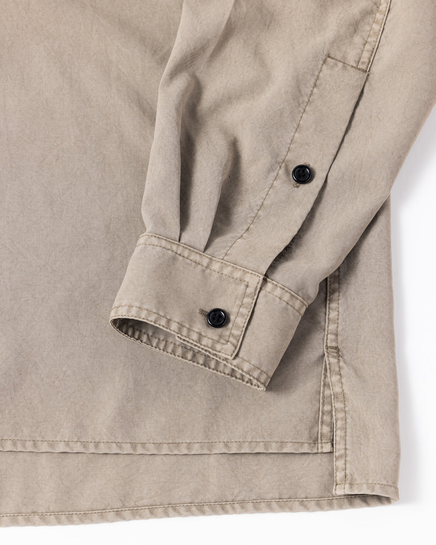 ポリエステル100％ながら、綿のような質感と軽量性を備えた高機能素材を採用。タスラン加工糸を使用したポリエステルオックスは、シワになりにくく速乾性にも優れています。本来染色が困難な素材に特殊顔料染めを施すことで、化繊特有の光沢を抑え、ナチュラルで奥行きのある絶妙なフェード感と落ち着いた表情を実現しました。

A high-performance piece crafted from polyester oxford, offering a cotton-like touch with quick-dry and wrinkle-resistant benefits. This GRAY BEIGE item features a special pigment dye—a rare process for polyester—achieving a sophisticated, faded texture and a matte finish that perfectly balances technical utility with a natural, lived-in aesthetic.