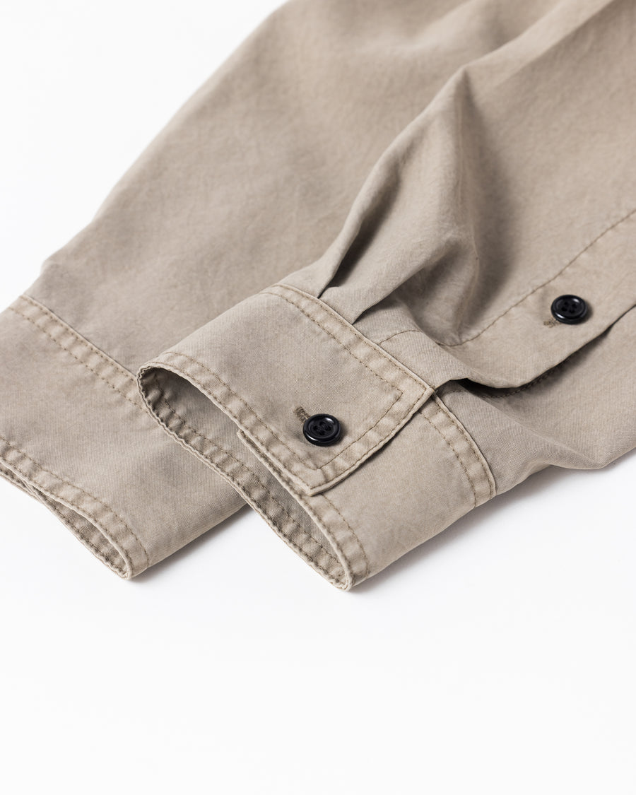 ポリエステル100％ながら、綿のような質感と軽量性を備えた高機能素材を採用。タスラン加工糸を使用したポリエステルオックスは、シワになりにくく速乾性にも優れています。本来染色が困難な素材に特殊顔料染めを施すことで、化繊特有の光沢を抑え、ナチュラルで奥行きのある絶妙なフェード感と落ち着いた表情を実現しました。

A high-performance piece crafted from polyester oxford, offering a cotton-like touch with quick-dry and wrinkle-resistant benefits. This GRAY BEIGE item features a special pigment dye—a rare process for polyester—achieving a sophisticated, faded texture and a matte finish that perfectly balances technical utility with a natural, lived-in aesthetic.