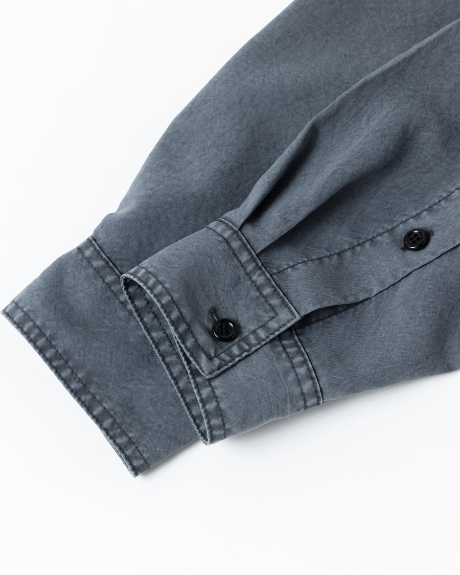 ポリエステル100％ながら、綿のような質感と軽量性を備えた高機能素材を採用。タスラン加工糸を使用したポリエステルオックスは、シワになりにくく速乾性にも優れています。本来染色が困難な素材に特殊顔料染めを施すことで、化繊特有の光沢を抑え、ナチュラルで奥行きのある絶妙なフェード感と落ち着いた表情を実現しました。

A high-performance piece crafted from polyester oxford, offering a cotton-like touch with quick-dry and wrinkle-resistant benefits. This GRAY BEIGE item features a special pigment dye—a rare process for polyester—achieving a sophisticated, faded texture and a matte finish that perfectly balances technical utility with a natural, lived-in aesthetic.