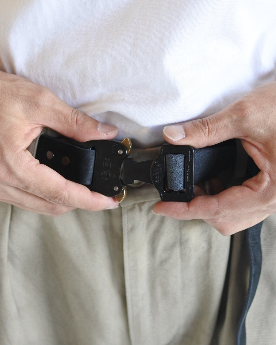 岡山県を拠点とするレザーブランド〈BRASSBOUND〉とのコラボレーションによる「COBRA BUCKLE LEATHER BELT TYPE2」。世界最高水準の安全性と耐久性を誇るコブラバックルを採用し、ワンタッチでの着脱が可能です。ベルト本体にはヌメカウレザーを使用。空打ち加工と吟面の仕上げにより、自然な風合いと経年変化を楽しめる一本に仕上げています。The COBRA BUCKLE LEATHER BELT TYPE2 is a collaboration with the Okayama-based leather brand BRASSBOUND.It features a Cobra Buckle known for world-class safety and durability, allowing quick locking and releasing.