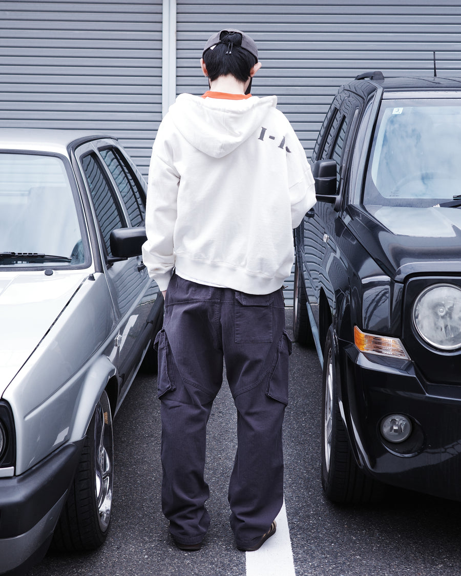 ミリタリートラウザーズをベースに、シルエットを現代的にリファイン。印象的な斜めのカーゴポケットが、立体感と実用性を両立させています。裾にかけて緩やかに絞られたテーパードラインにより、無骨ながらも洗練された印象に。素材には肌馴染みの良い10sヘリンボンを採用し、ストーンバイオウォッシュで柔らかな風合いとこなれ感を引き出しました。

Military trousers refined with a modern tapered silhouette. The distinctive slanted cargo pockets offer both practical utility and a structured look. Crafted from soft, classic 10s herringbone, this CHARCOAL pair has been treated with a stone bio-wash, providing a comfortable, worn-in texture and a sophisticated take on rugged style.