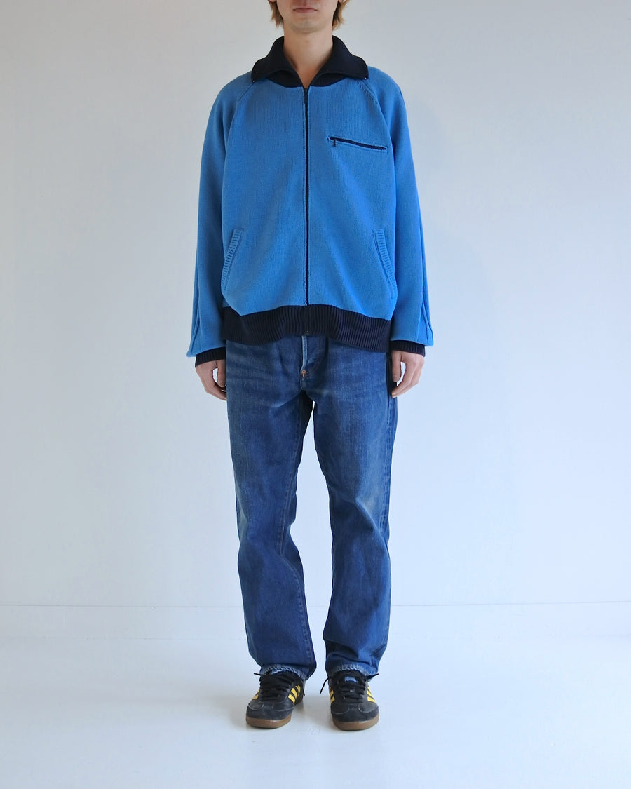 コットンニットを使用したドライバーズニット。
太番手の強撚糸による特殊な天竺編みで、適度なハリと風合いを持たせています。
ゆとりのある身幅ながら、アウターのインナーとしても使いやすいバランスの取れたシルエットに仕上げました。コットン素材のためホームクリーニングも可能です。
カラーは鮮やかなスカイブルー。