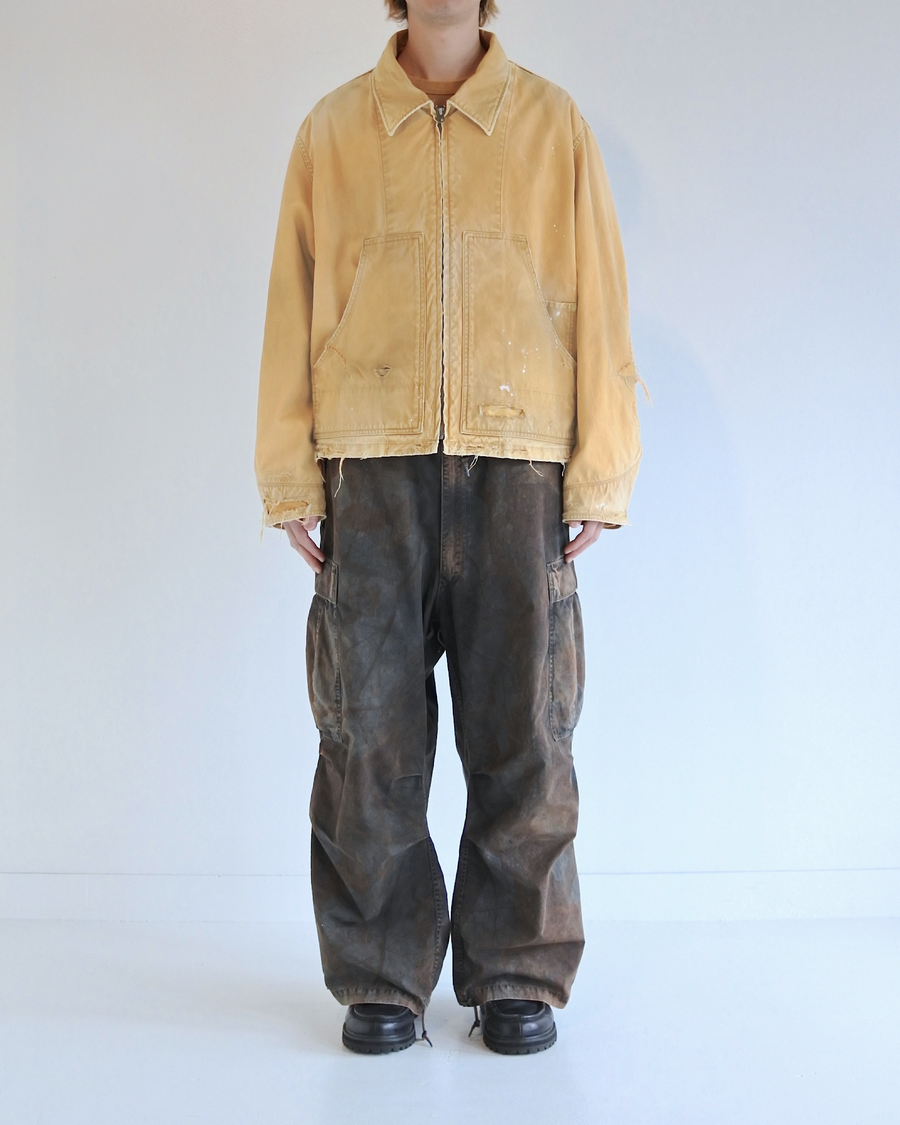 【 商品名：リメイクデトロイトダックジャケット 】

本製品は、ゆとりのある身幅とややクロップド丈に設計されたイエローカラーのジャケットで、インナーアイテムとのレイヤードを楽しめるバランスの良いシルエットが特徴です。生地には頒布の中でも最も薄手の11号帆布生地を使用しており、強度・耐久性に優れるとともに、着用を重ねるごとにアタリなどの経年変化を味わえる素材です。さらに、水や薬品の使用量を抑えながら生地の凹凸部分のアタリを強調し、同時に自然な脱色感を生み出す特殊エイジング加工を施し、加えてサンフェードによるダメージ加工も行うことで、より深みのある表情に仕上げています。