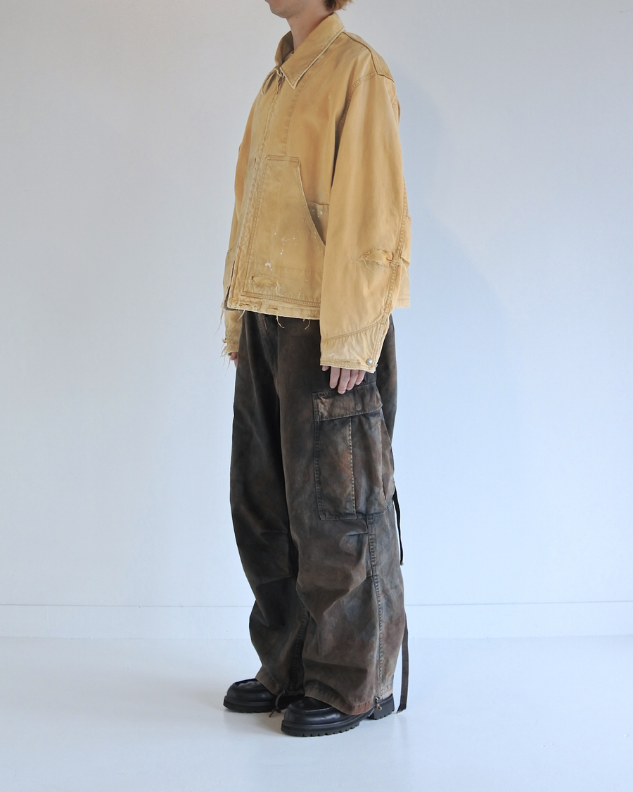 【 商品名：リメイクデトロイトダックジャケット 】

本製品は、ゆとりのある身幅とややクロップド丈に設計されたイエローカラーのジャケットで、インナーアイテムとのレイヤードを楽しめるバランスの良いシルエットが特徴です。生地には頒布の中でも最も薄手の11号帆布生地を使用しており、強度・耐久性に優れるとともに、着用を重ねるごとにアタリなどの経年変化を味わえる素材です。さらに、水や薬品の使用量を抑えながら生地の凹凸部分のアタリを強調し、同時に自然な脱色感を生み出す特殊エイジング加工を施し、加えてサンフェードによるダメージ加工も行うことで、より深みのある表情に仕上げています。