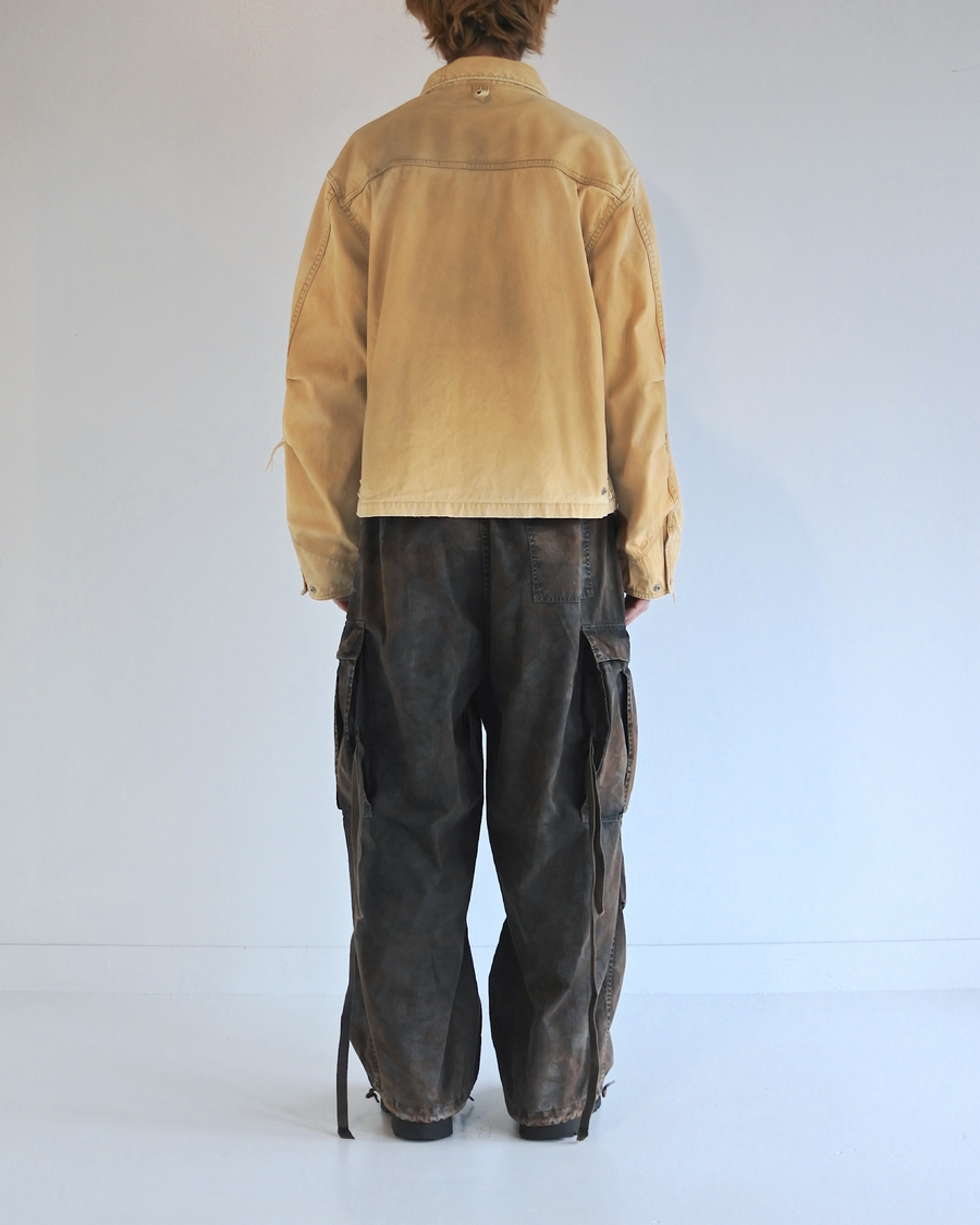 【 商品名：リメイクデトロイトダックジャケット 】

本製品は、ゆとりのある身幅とややクロップド丈に設計されたイエローカラーのジャケットで、インナーアイテムとのレイヤードを楽しめるバランスの良いシルエットが特徴です。生地には頒布の中でも最も薄手の11号帆布生地を使用しており、強度・耐久性に優れるとともに、着用を重ねるごとにアタリなどの経年変化を味わえる素材です。さらに、水や薬品の使用量を抑えながら生地の凹凸部分のアタリを強調し、同時に自然な脱色感を生み出す特殊エイジング加工を施し、加えてサンフェードによるダメージ加工も行うことで、より深みのある表情に仕上げています。