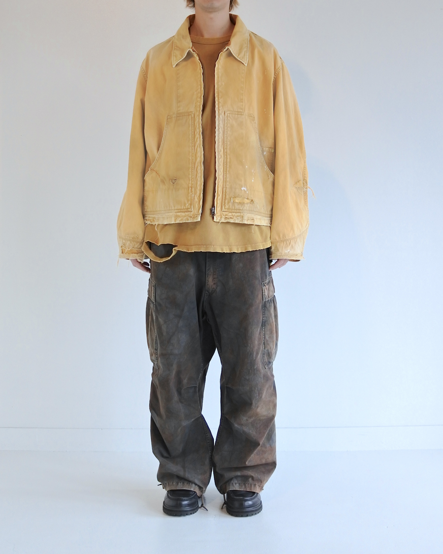 【 商品名：リメイクデトロイトダックジャケット 】

本製品は、ゆとりのある身幅とややクロップド丈に設計されたイエローカラーのジャケットで、インナーアイテムとのレイヤードを楽しめるバランスの良いシルエットが特徴です。生地には頒布の中でも最も薄手の11号帆布生地を使用しており、強度・耐久性に優れるとともに、着用を重ねるごとにアタリなどの経年変化を味わえる素材です。さらに、水や薬品の使用量を抑えながら生地の凹凸部分のアタリを強調し、同時に自然な脱色感を生み出す特殊エイジング加工を施し、加えてサンフェードによるダメージ加工も行うことで、より深みのある表情に仕上げています。