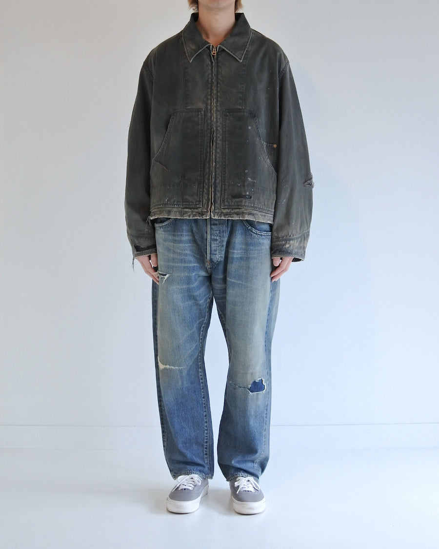 【 商品名：リメイクデトロイトダックジャケット 】

本製品は、ゆとりのある身幅とややクロップド丈に設計されたブラックカラーのジャケットで、インナーアイテムとのレイヤードを楽しめるバランスの良いシルエットが特徴です。生地には頒布の中でも最も薄手の11号帆布生地を採用しており、強度・耐久性に優れ、着用を重ねるごとにアタリなどの経年変化を味わえる素材です。さらに、水や薬品の使用量を抑えながら生地の凹凸部分のアタリを強調し、同時に自然な脱色感を生み出す特殊エイジング加工を施し、加えてサンフェードによるダメージ加工を加えることで、より奥行きのある表情に仕上げています。