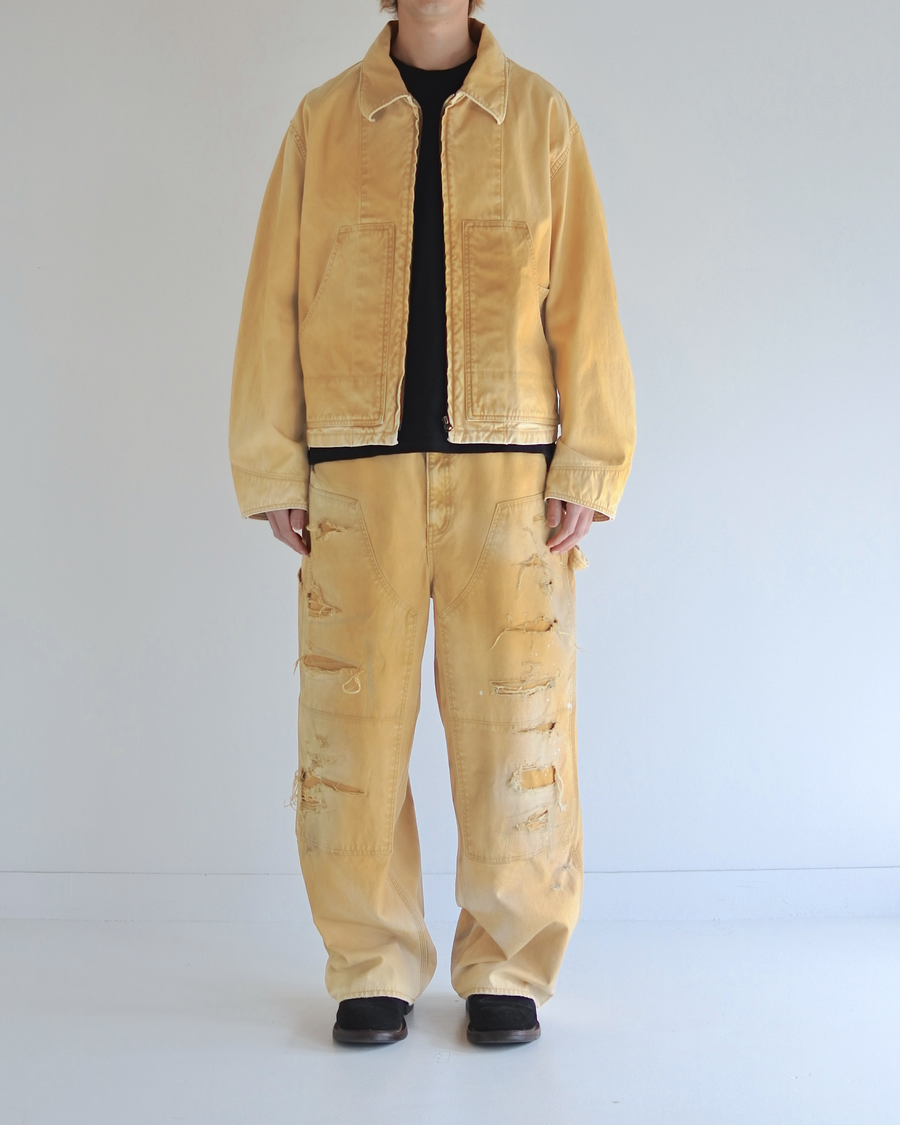 シルエットはゆとりのある身幅とややクロップド丈で設計しており、イエローカラーの鮮やかなトーンがレイヤードスタイルをより引き立てます。インナーアイテムとの重ね着がしやすいバランスに仕上げています。
生地には頒布の中で最も薄手の11号帆布を採用しており、強度・耐久性に優れるだけでなく、着用を重ねるごとにアタリなどの経年変化を楽しめる素材です。また、特殊エイジング加工を施すことで、水や薬品の使用量を抑えながら生地の凹凸が強調され、イエローの色味に自然なフェード感を加えています。