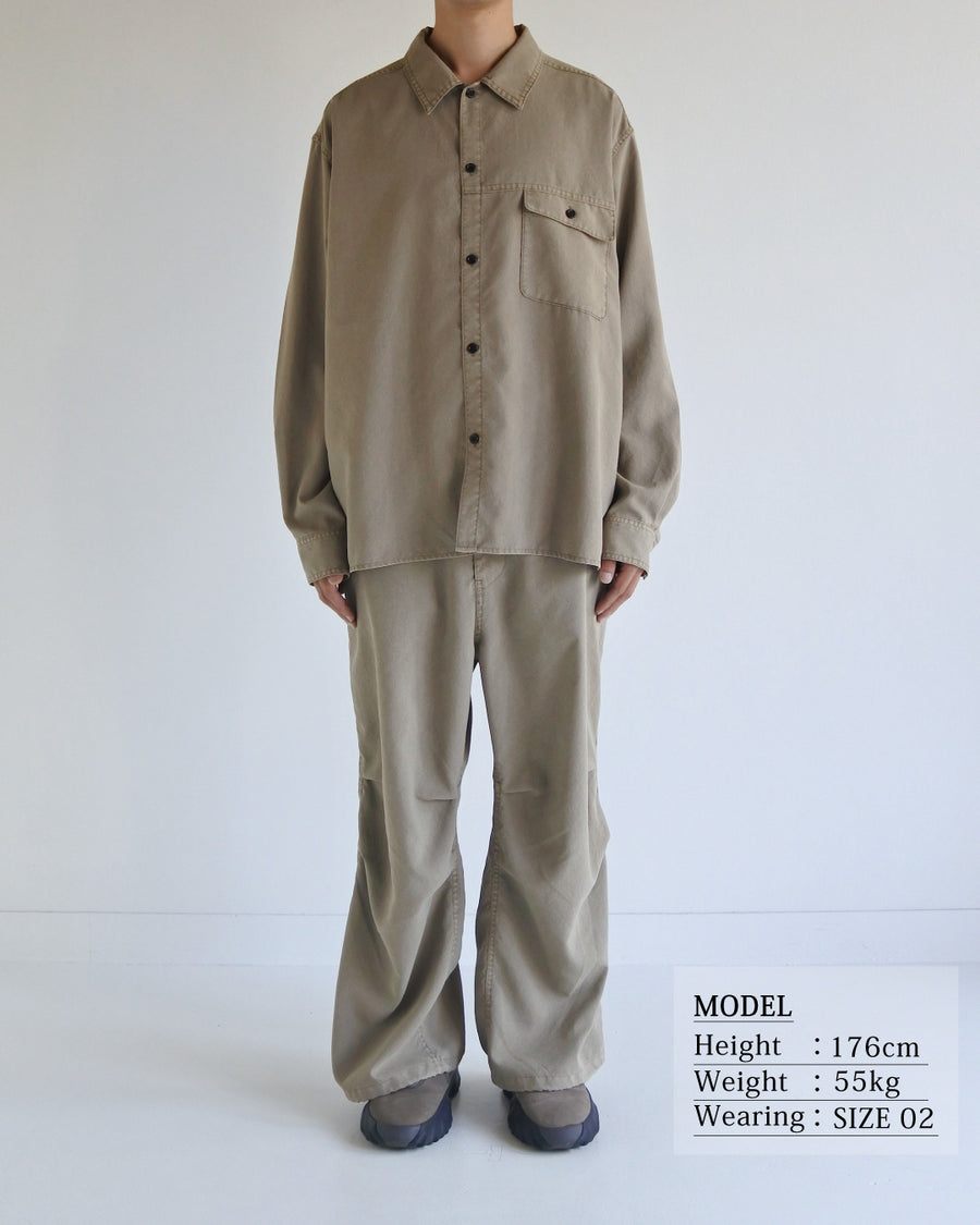 ポリエステル100％ながら、綿のような質感と軽量性を備えた高機能素材を採用。タスラン加工糸を使用したポリエステルオックスは、シワになりにくく速乾性にも優れています。本来染色が困難な素材に特殊顔料染めを施すことで、化繊特有の光沢を抑え、ナチュラルで奥行きのある絶妙なフェード感と落ち着いた表情を実現しました。

A high-performance piece crafted from polyester oxford, offering a cotton-like touch with quick-dry and wrinkle-resistant benefits. This GRAY BEIGE item features a special pigment dye—a rare process for polyester—achieving a sophisticated, faded texture and a matte finish that perfectly balances technical utility with a natural, lived-in aesthetic.