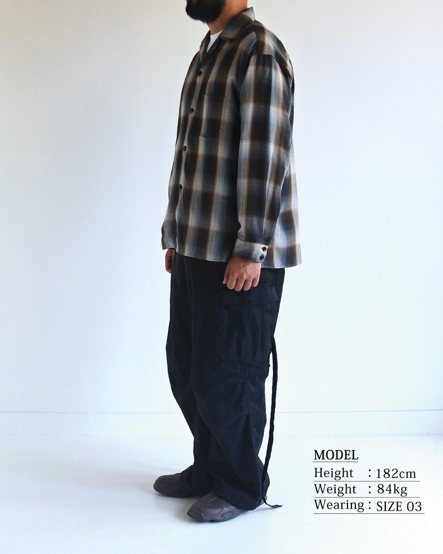 オンブレチェック柄が目を惹くオープンカラーシャツ。生地が持つ自然なドレープ感を活かし、リラックス感のあるゆとりを持たせたシルエットに仕上げました。素材にはタテ・ヨコ共にレーヨン糸を使用したレーヨンチェックを採用。非常に優れた落ち感と、袖を通した瞬間に感じる滑らかで心地よい肌触りが、上質なリラックススタイルを演出します。

An open-collar shirt featuring a classic ombre check pattern. The relaxed silhouette highlights the natural drape and fluid movement of the fabric. Crafted from a high-quality rayon check weave, this BLUE CHECK piece is characterized by its exceptional softness and smooth touch, offering a sophisticated look with an effortlessly comfortable feel.