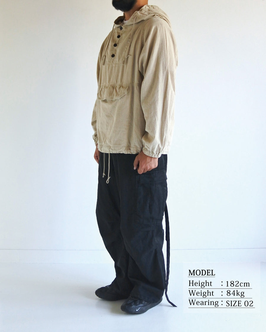フード口のボタンの開閉により、首周りのニュアンスを自在に調整できる一着。素材には、麻カスや節を活かしたネップ糸を織り交ぜたコットンリネンチェックを採用しました。ドライタッチな生地にワンウォッシュを施すことで、麻特有のハリ感を残しつつ、肌馴染みの良い柔らかな風合いと豊かな表情を引き出しています。

This piece features adjustable hood buttons to alternate between a clean look and a relaxed neckline. Crafted from a cotton-linen check weave with rustic nep yarns, it highlights the natural texture of the fibers. The BEIGE fabric is one-washed to balance a crisp, dry touch with a soft, broken-in feel, creating a sophisticated yet comfortable aesthetic.