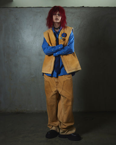 【 商品名：ダブルニーダックペインターパンツ 】

本製品は、レングスをやや長めに設定したイエローカラーのペインターパンツです。ウエスト部分にはナイロンオックス生地で切り替えを施し、ワーク感を抑えたデザインに仕上げています。生地には頒布の中でも最も薄手の11号帆布生地を使用しており、強度・耐久性に優れるだけでなく、着用を重ねるごとにアタリなどの経年変化を楽しめる素材です。また、水や薬品の使用量を抑えつつ生地の凹凸部分のアタリを強調し、同時に自然な脱色感を生み出す特殊エイジング加工を施しています。